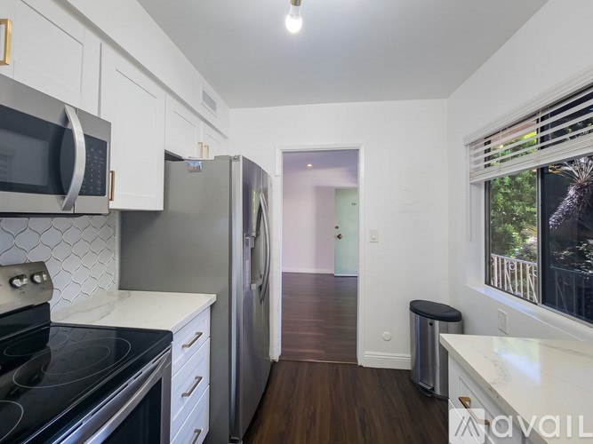 A kitchen with a black stove top oven and a silver refrigerator.