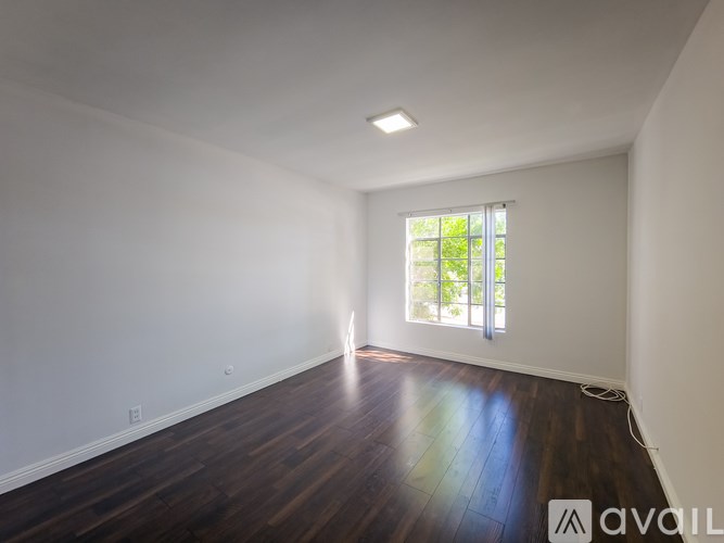 A room with wooden floors and a window letting in natural light.
