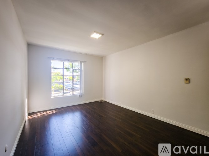 A room with wooden floors and a window letting in natural light.