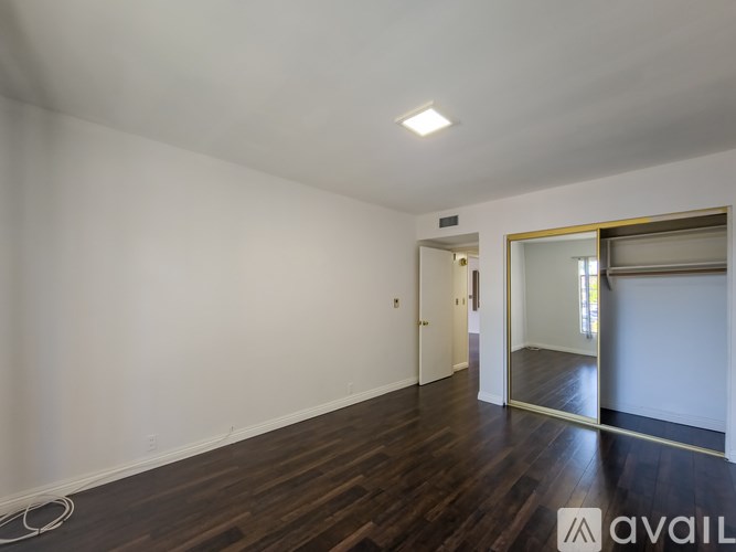 A spacious room with wooden floors and white walls.