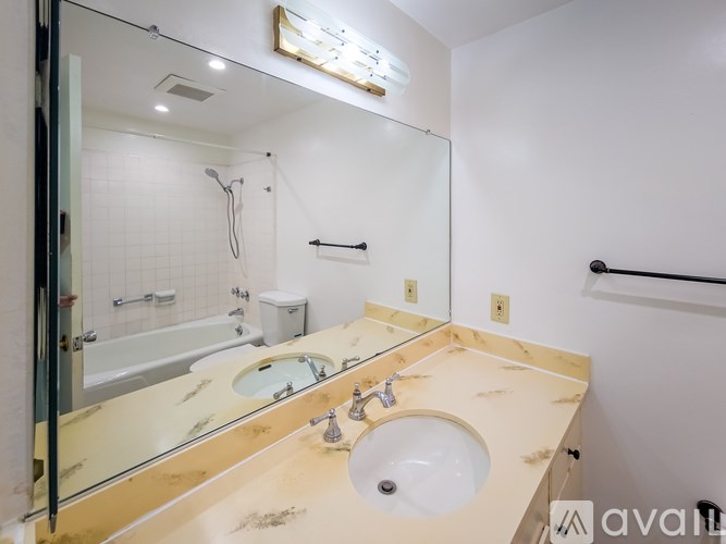 A bathroom with a wooden vanity, a sink, a mirror, and a shower.