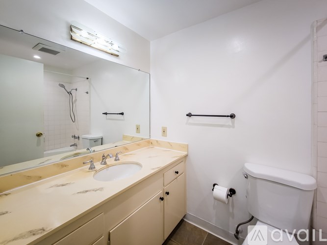A bathroom with a sink, mirror, and toilet paper roll.