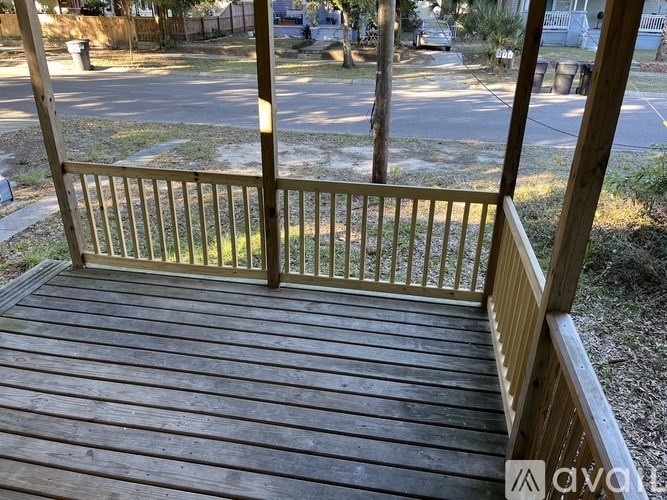 A wooden deck with a railing overlooking a street.
