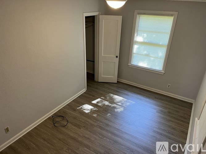A room with a wooden floor and a window with blinds.