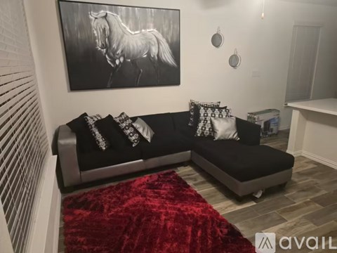 A living room with a grey couch and a black and white horse picture on the wall.