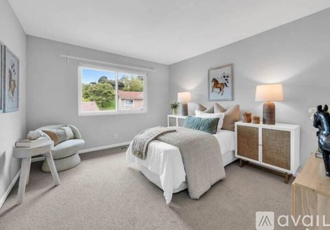 A bedroom with a large bed, a window with a view, and a wooden cabinet.