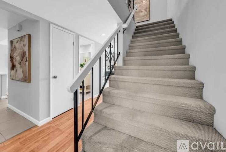 A staircase with a black railing and beige carpeted steps.
