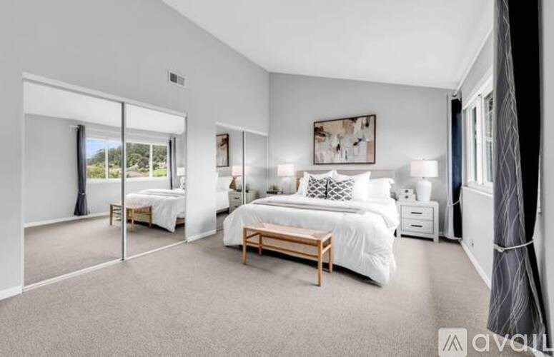 A bedroom with a large bed and a sliding glass door leading to a balcony.