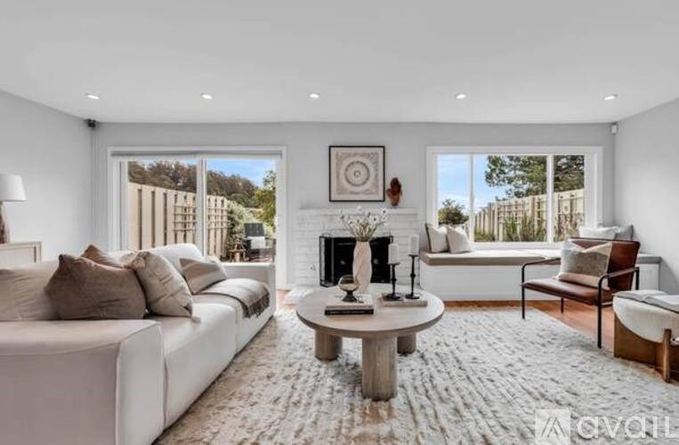 A modern living room with a white sofa, a coffee table, and a fireplace.