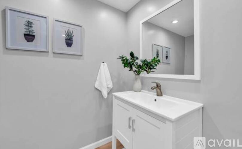 A white bathroom vanity with a mirror and a potted plant.
