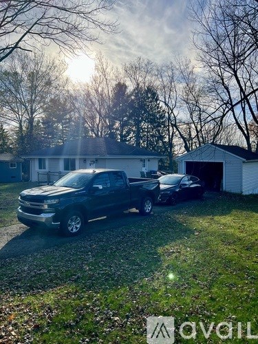 A black truck is parked in front of a white house.