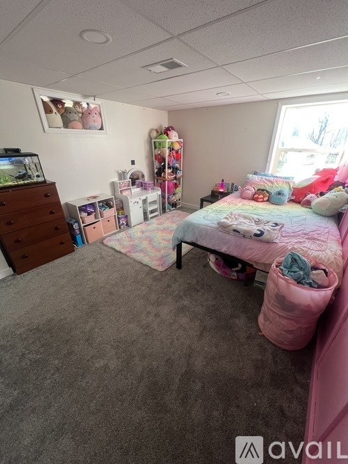 A bedroom with a bed, dresser, and window.