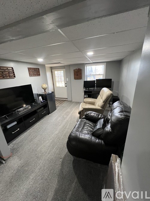 A living room with a black leather couch and a television.