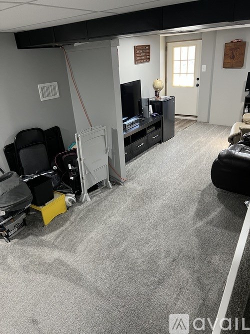 A room with a grey carpet and a television on a stand.