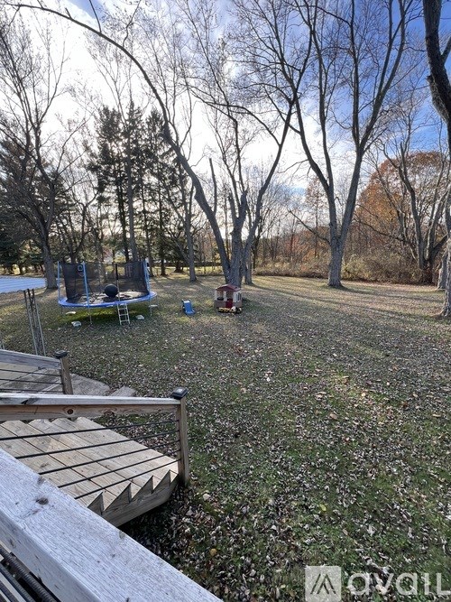 A backyard with a wooden deck and a picnic table.