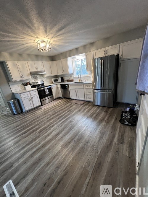 A kitchen with wooden floors and white cabinets.