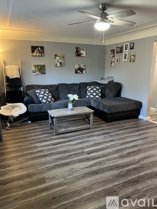 A living room with a grey couch, a coffee table, and pictures on the wall.
