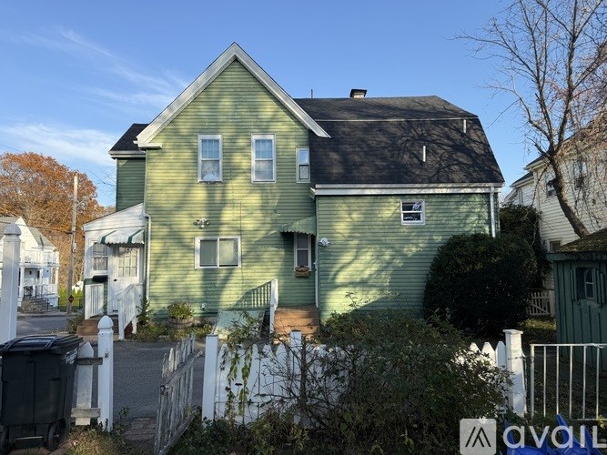 A green house with a white picket fence in front.
