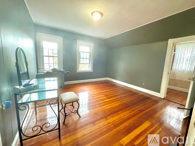 A room with a wooden floor and a glass table with a mirror on it.