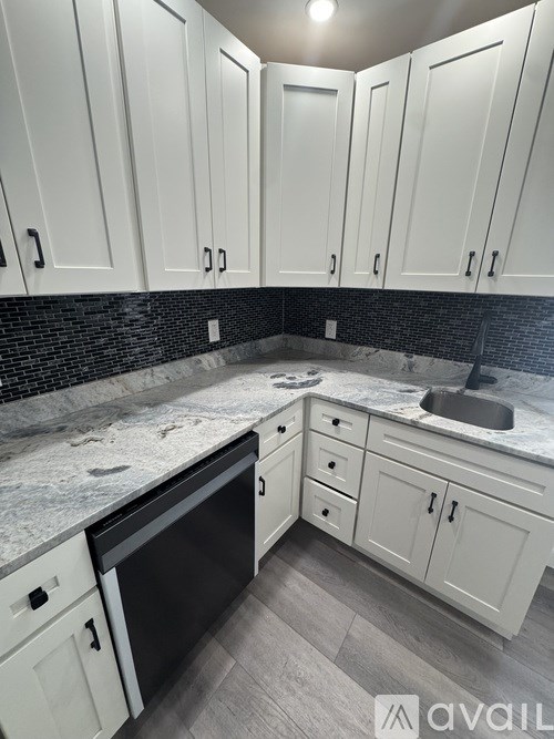 A kitchen with white cabinets and a black dishwasher.