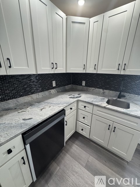A kitchen with white cabinets and a black dishwasher.