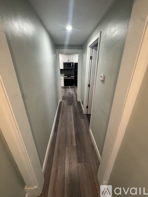 A long hallway with wood floors and white walls.