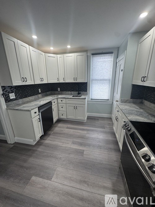 A kitchen with white cabinets and a marble countertop.