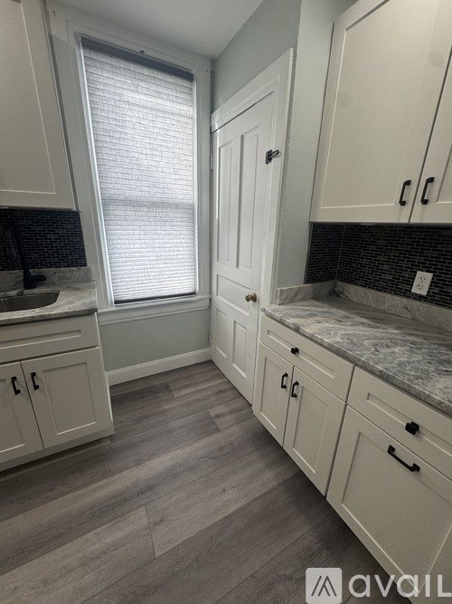 A kitchen with white cabinets and a marble countertop.