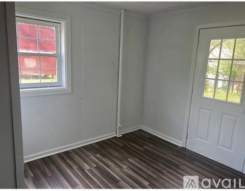 A room with a white door and a window with a red curtain.