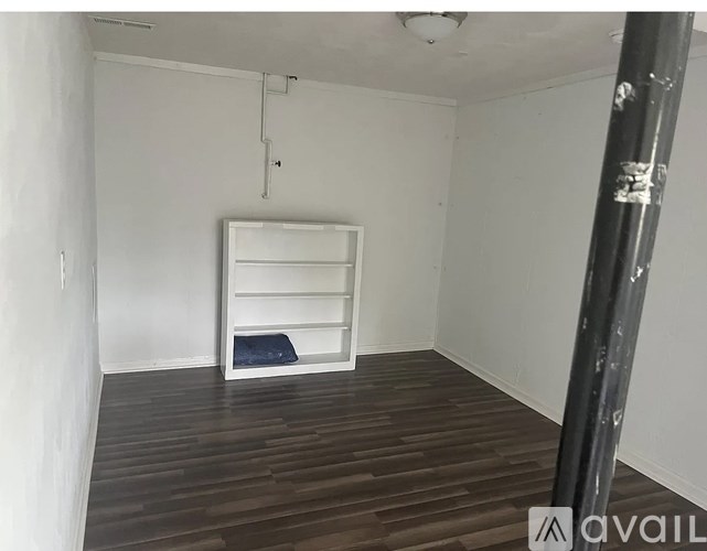 A room with a bed and a wooden floor.