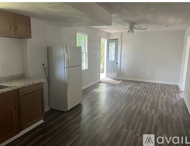 A kitchen with a refrigerator, wooden cabinets, and a ceiling fan.