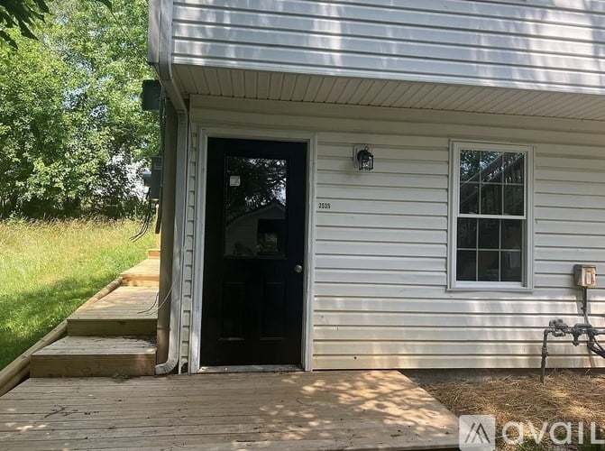 A white house with a black door and a small window on the side.