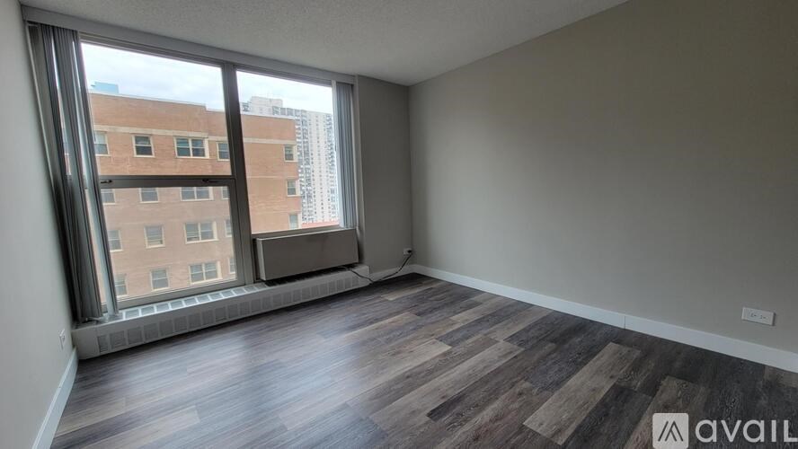 A room with wooden flooring and a large window overlooking a cityscape.