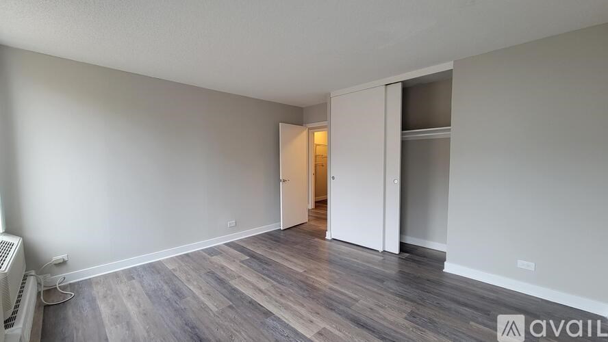 A room with a wooden floor and a white wall with a doorway leading to another room.