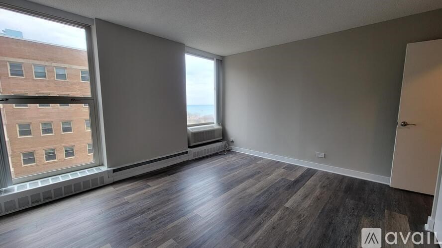 A room with wooden flooring and a large window overlooking a cityscape.