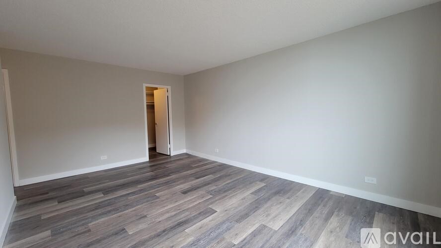 A room with wooden flooring and a doorway leading to another room.