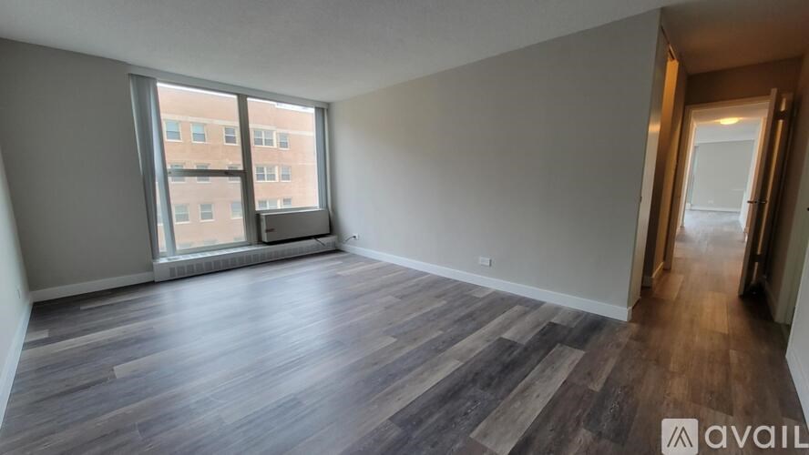 A room with wooden flooring and a large window overlooking a building.