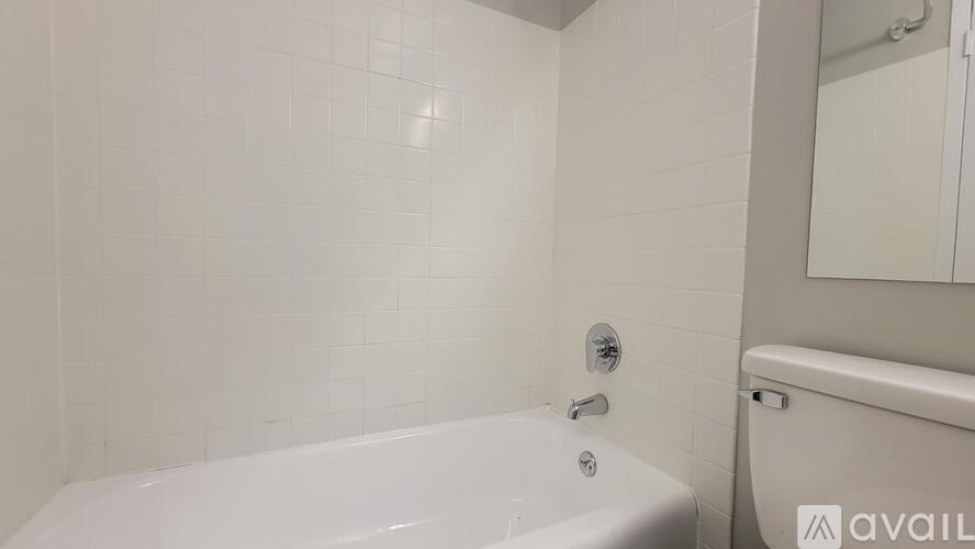 A white bathtub in a bathroom with a white tiled wall.