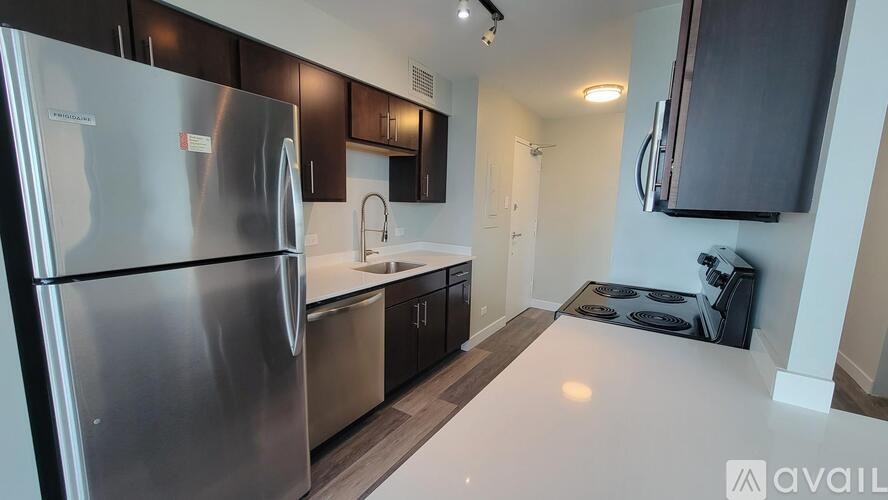 A modern kitchen with a stainless steel refrigerator and dark brown cabinets.