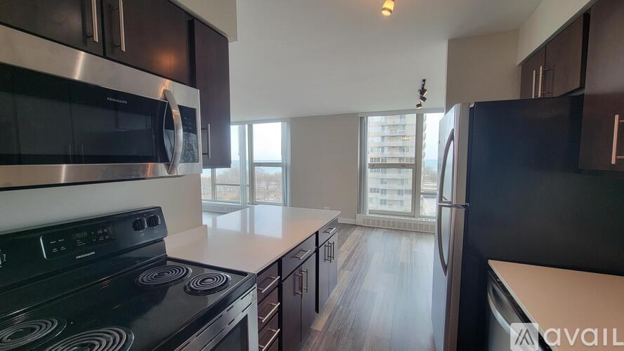 A modern kitchen with dark wood cabinets and stainless steel appliances.