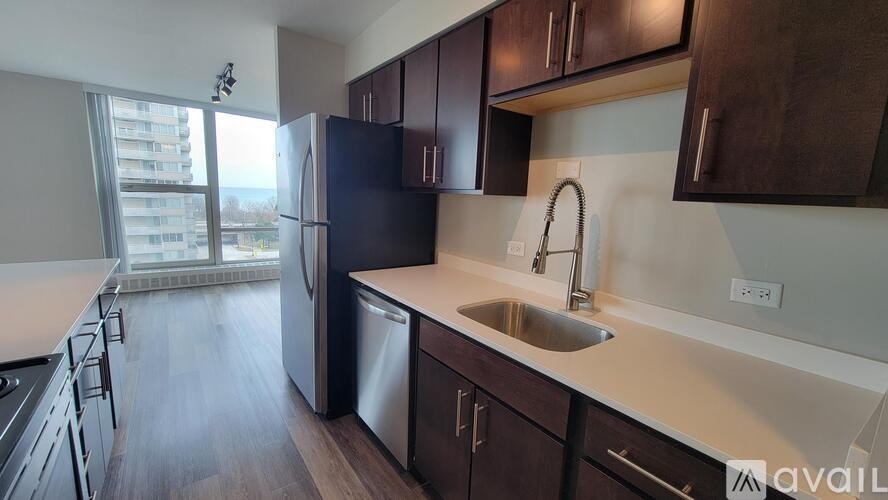 A kitchen with dark wood cabinets and a stainless steel refrigerator.