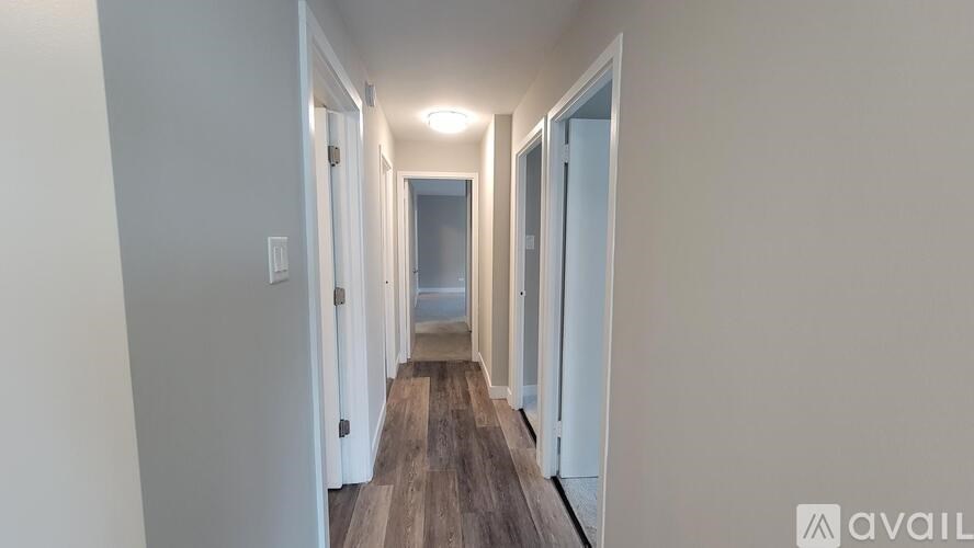 A long hallway with doors on both sides and a wooden floor.