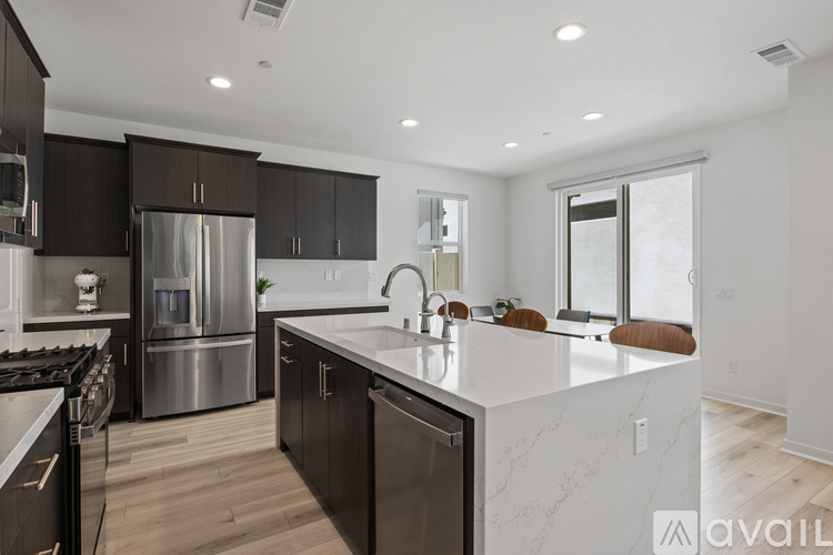 A modern kitchen with a white countertop and stainless steel appliances.
