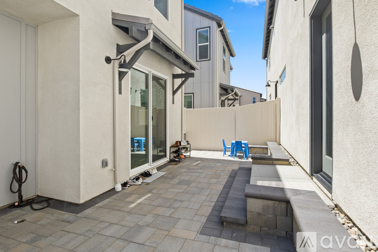 A patio with a bench and a table with chairs is surrounded by buildings.