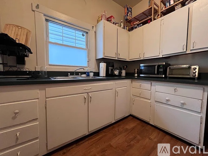 A kitchen with white cabinets and black countertops.