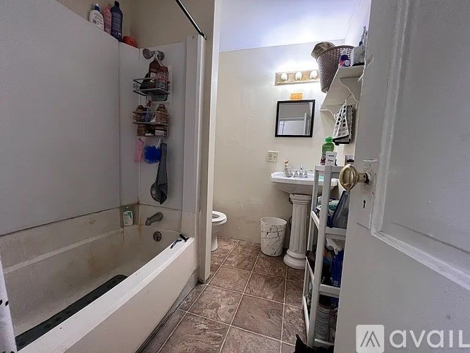 A bathroom with a tub, toilet, sink and a shelf with bottles.