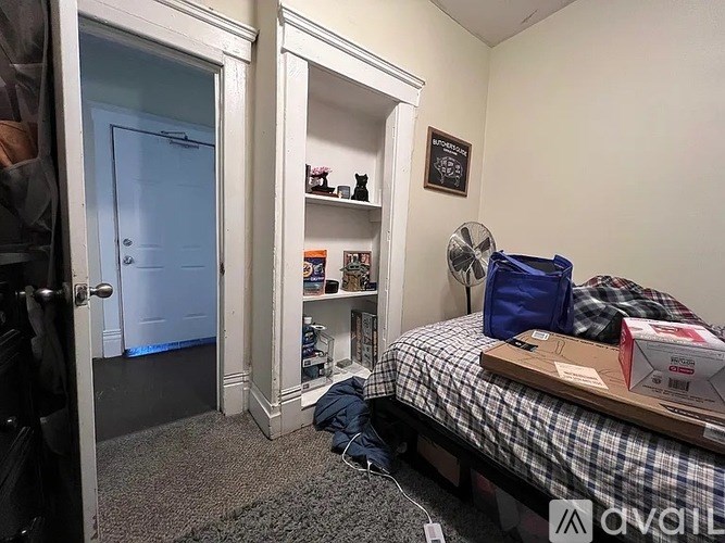 A bedroom with a bed, a fan, and a door.