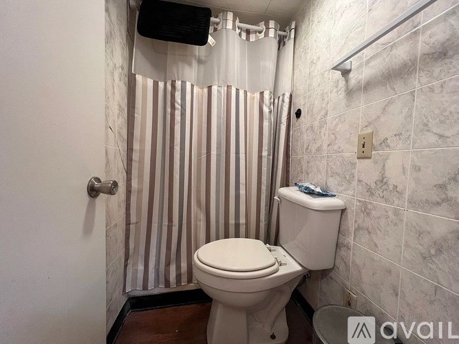 A white toilet in a bathroom with a striped shower curtain.