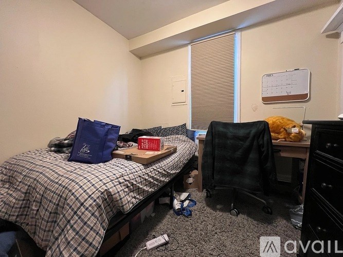 A bedroom with a bed, a chair, and a desk with a computer.