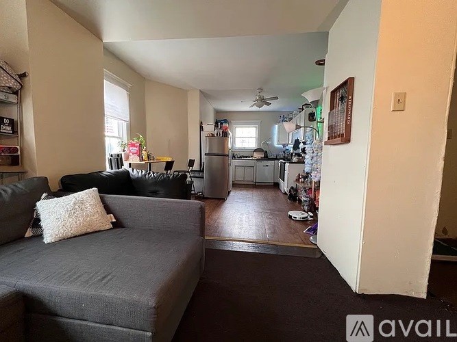 A living room with a grey couch and a kitchen in the background.